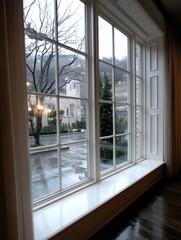 Fototapeta premium Rainy Day View Through Window: Lush Garden and Historic Architecture in Soft Focus