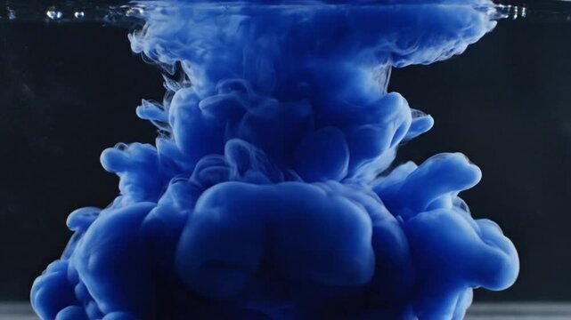 Blue ink cloud spreading underwater, viewed from the side, capturing the fluid dynamics and abstract beauty of the submerged scene
