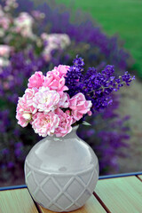 różowe róże i fioletowa lawenda w wazonie na rozmytym tle, róże i lawenda w małym wazonie na tle ogrodu, pink roses and purple lavender in a vase on a blurry background © kateej