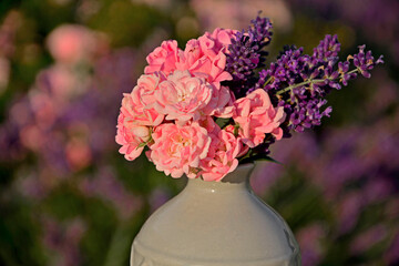 różowe róże i fioletowa lawenda w wazonie na rozmytym tle, róże i lawenda w małym wazonie na tle ogrodu, pink roses and purple lavender in a vase on a blurry background © kateej