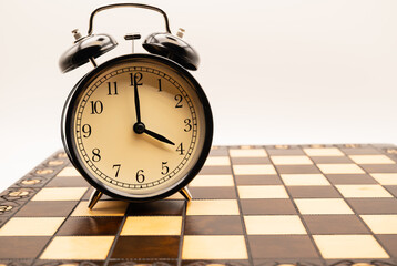 Alarm clock showing 4 o'clock on a chessboard symbolizing time management, strategy, leadership and decision making in business planning, deadlines and strategic thinking.