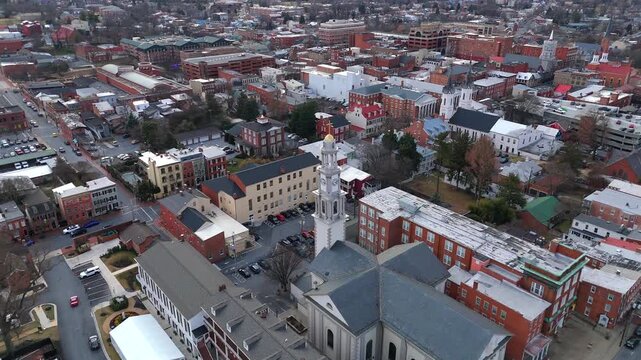 High angle drone shot of an urban neighborhood with a church steeple in Frederick Maryland