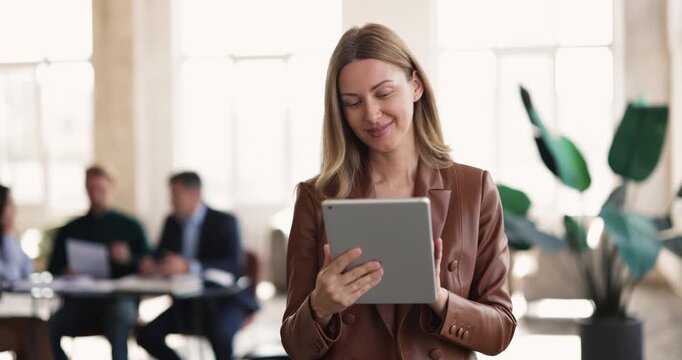 Focused businesswoman working on tablet in office, reviewing project document, check online presentation slides before meeting, evaluating data or leading business communication with corporate client