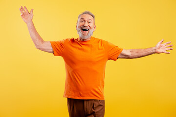 Fototapeta premium Happy bearded senior man wearing colorful clothes looking at camera isolated on yellow background