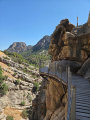 Elevated walkway attached to massive rock formations in a mountain canyon. Concept of adventure travel, safety paths and outdoor exploration.