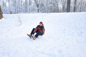 Teen sledder sitting on snow hill ready to slide downhill