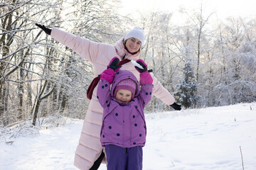 Loving mother and daughter hugging and playing together in magical snow covered winter woods
