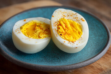 Hard boiled eggs cut in half on a blue plate sitting on a wooden surface in a kitchen setting