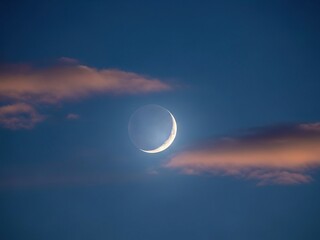 Obraz premium Crescent moon shining brightly in a serene evening sky with clouds