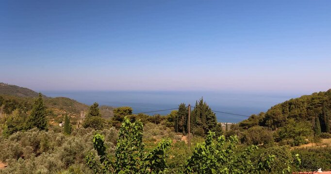 Panoramic hilltop view overlooking the deep blue sea and lush greenery under a clear sky in a Mediterranean setting.