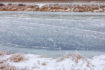Broad river in winter with extensive frazil ice accumulation and smooth ice zones showing active freezing dynamics