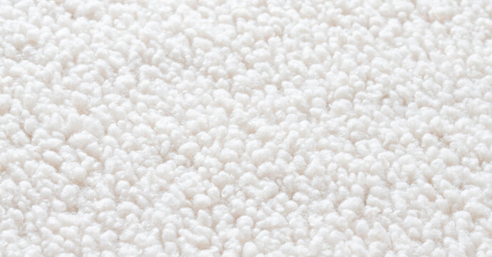 Soft white sherpa faux fur texture background with fluffy curly wool fibers for cozy winter fashion designs