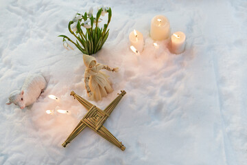 Naklejka premium Imbolc celebration with brigid's cross, snowdrops, and candles in snow