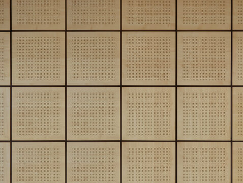 Modular wooden acoustic false ceiling panels in interior space. Geometric grid design texture, sound absorption, noise control, contemporary architectural aesthetic, auditoriums, offices, facilities. 