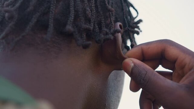 Hidden Tactical Operative, Operative Hides Earpiece Beneath Dreadlocks For Covert Operations, Black Operative Discreetly Secures Earpiece Beneath Hairstyle During Mission Activities