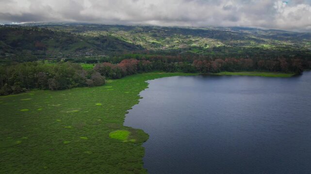 Aerial Hyperlapse of Tropical Lake and Wetlands Surrounded by Green Mountains and Low Clouds