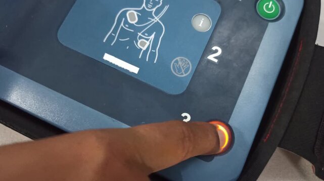 pressing the AED's shock button to deliver an electric shock to a heart attack patient