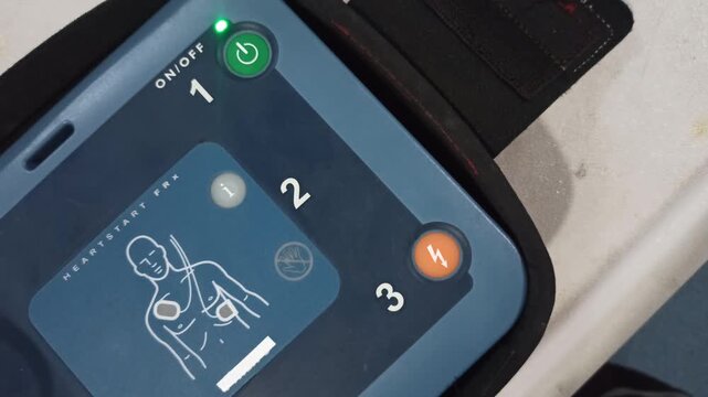 pressing the AED's shock button to deliver an electric shock to a heart attack patient