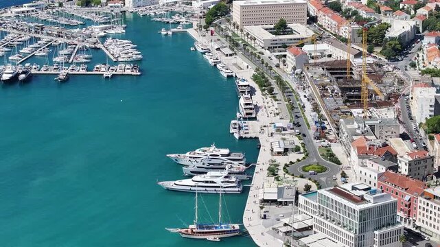 Aerial drone view of boats, yachts, and people walking along Split west coast promenade on a sunny day.