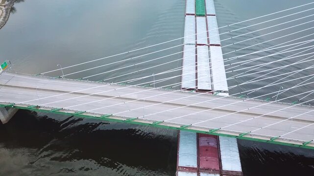Aerial of a coal barge pushed by tugboat moving up the Mississippi River near Burlington Iowa with suspension bridge foreground.