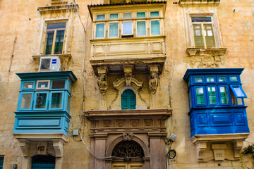 Close up of an old stone building with traditional blue and white wooden balconies in Valletta, Malta