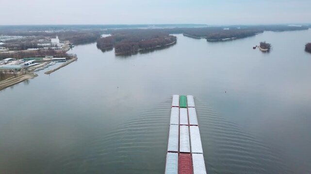 Aerial of a coal barge pushed by tugboat moving up the Mississippi River near Burlington Iowa with suspension bridge foreground.