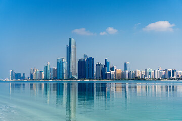 Obraz premium Abu Dhabi, wide view of modern city skyline with skyscrapers reflected on calm waterfront