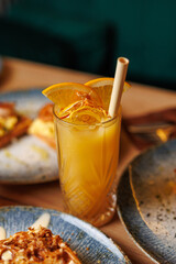 Enjoy a refreshing drink with orange slices and a straw alongside delicious dishes from various cuisines