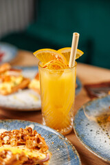 Enjoying fresh citrus drink with dishes from various cuisines on table during afternoon gathering