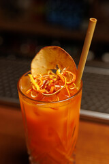 Refreshing cocktail garnished with dried fruit and citrus twists served in a classic glass at a bar setting