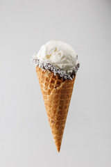 Enjoy creamy vanilla ice cream cone with chocolate and coconut toppings during a warm summer day