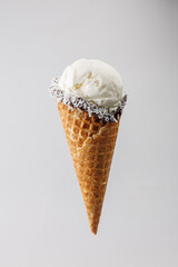 Delicious ice cream cone with creamy vanilla and coconut topping displayed against a plain background