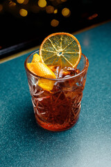 Enjoying a crafted cocktail with garnishes of orange and dried citrus on a vibrant bar surface