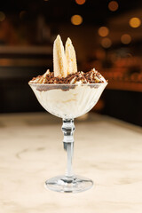 Delicious dessert served in a glass with banana slices and chocolate topping in a cozy dining setting