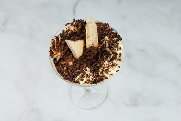 Delicious dessert showcases creamy layers, crunchy toppings, and rich chocolate in a stylish glass bowl at a casual dining spot