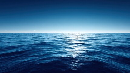 Obraz premium Vast blue ocean stretching towards a clear sky with sunlight reflecting on gentle waves