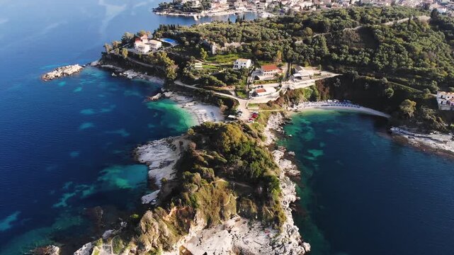 Aerial drone view of Kassiopi, coast sea village in northeast coast of Corfu island, Ionian Islands, Kerkyra, Greece in a summer sunny day, with marina, town, beach and castle, Greek landscape