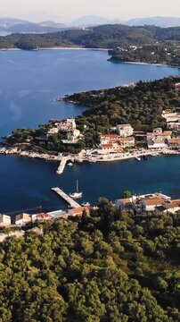Aerial drone view of Kassiopi, coast sea village in northeast coast of Corfu island, Ionian Islands, Kerkyra, Greece in a summer sunny day, with marina, town, beach and castle, Greek landscape