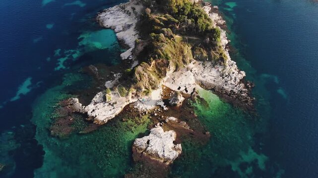 Aerial drone view of Kassiopi, coast sea village in northeast coast of Corfu island, Ionian Islands, Kerkyra, Greece in a summer sunny day, with marina, town, beach and castle, Greek landscape