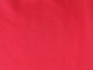 Fototapeta premium Red synthetic fabric texture with micro woven pattern, close-up textile background for sports and fashion design.