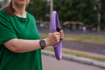 Woman exercising outdoors with fitness rings in a park during a sunny day