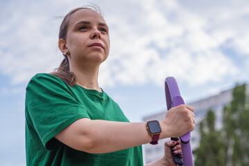Woman exercising outdoors with fitness rings in a park during a sunny day