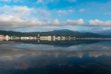 早朝の静かな琵琶湖　大津市のマンション群と雲が湖面に映る風景