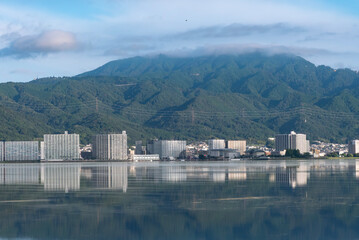 早朝の静かな琵琶湖　大津市のマンション群と雲が湖面に映る風景