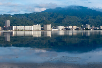 早朝の静かな琵琶湖　大津市のマンション群と雲が湖面に映る風景