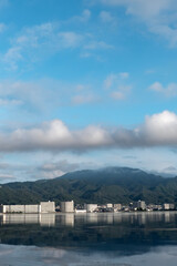 早朝の静かな琵琶湖　大津市のマンション群と雲が湖面に映る風景
