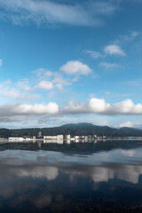 早朝の静かな琵琶湖　大津市のマンション群と雲が湖面に映る風景