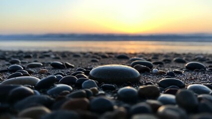 Serene Pebble Beach Sunset: A tranquil beach scene unveils, showcasing a collection of smooth, diverse pebbles in the foreground, kissed by the soft glow of a setting sun above the calm waters.