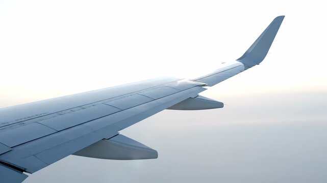 View of airplane wing above gray clouds during flight travel