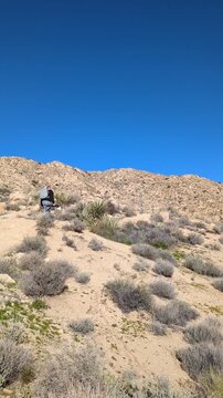 Hiker with backpack tripod hiking along desert ridge trail. Copy space